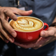 Man holds elaborate latte in mug